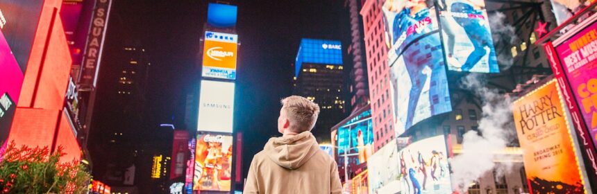 man standing on road infront of high-rise buildi