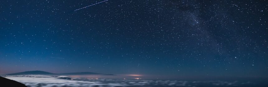 blue and black sky with stars and falling star at nighttime